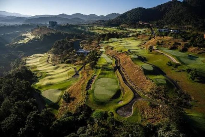 Vista aérea de una cancha de golf entre cerros boscosos